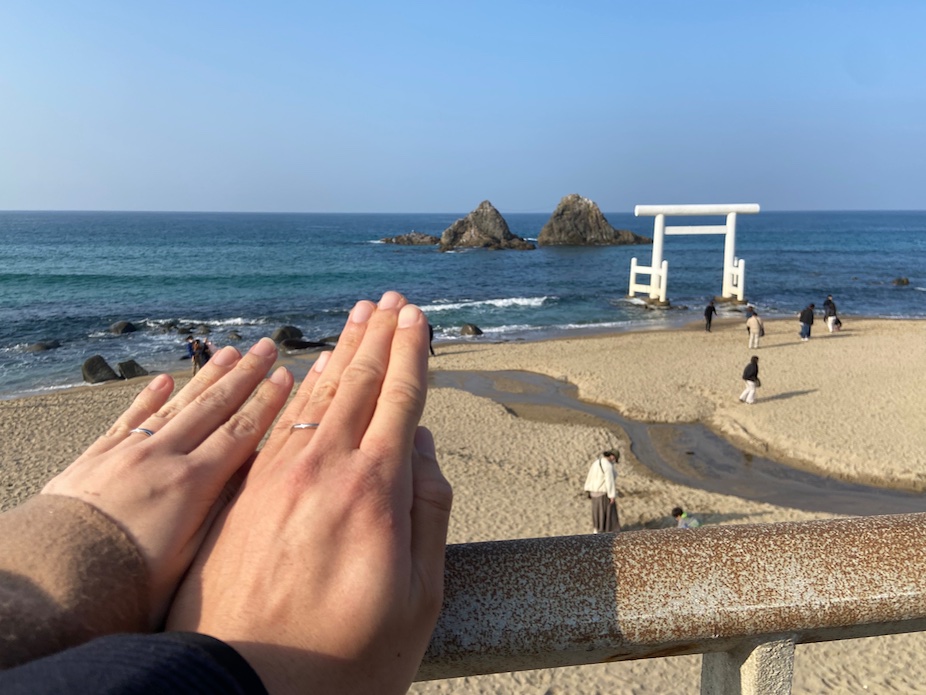 桜井二見ヶ浦夫婦岩を背景に結婚指輪をはめた2人の左手